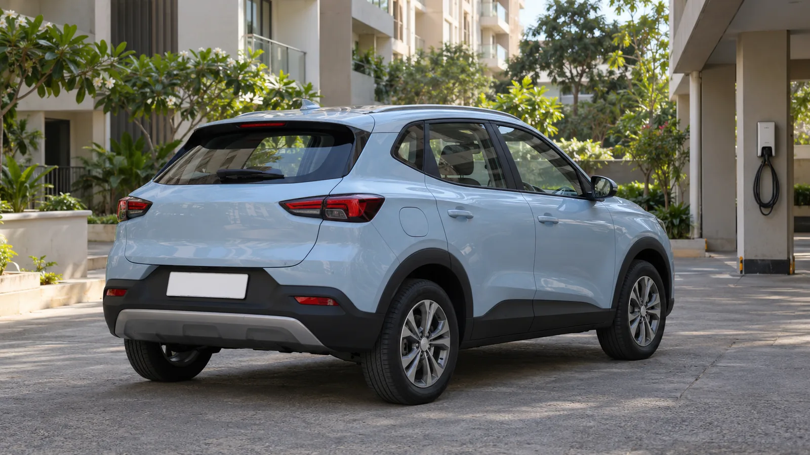 Illustrative unbranded pale blue electric crossover in an Indian apartment parking court with a wall charger in the background