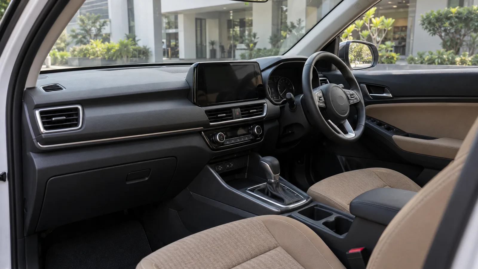 Generic unbranded right-hand-drive cabin with tan seats and a dark infotainment screen outside an Indian service building, illustrative scene
