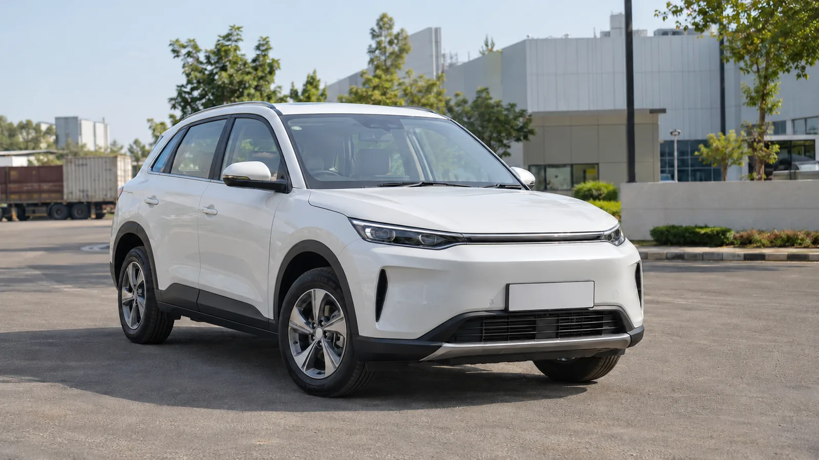 Illustrative unbranded white electric crossover outside a modern automotive factory in Gujarat